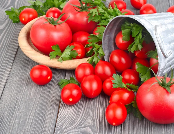 Fresh tomatoes and cherry and greens on a gray wooden background with space for the text. — Stock Photo, Image