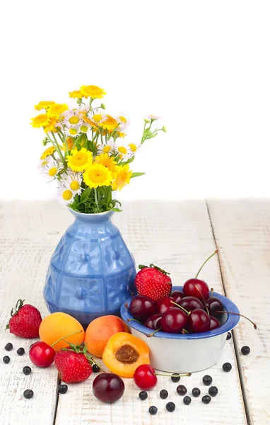 Fresh berries and bouquet of camomiles in a vase on a white background with space for the text. — Stock Photo, Image