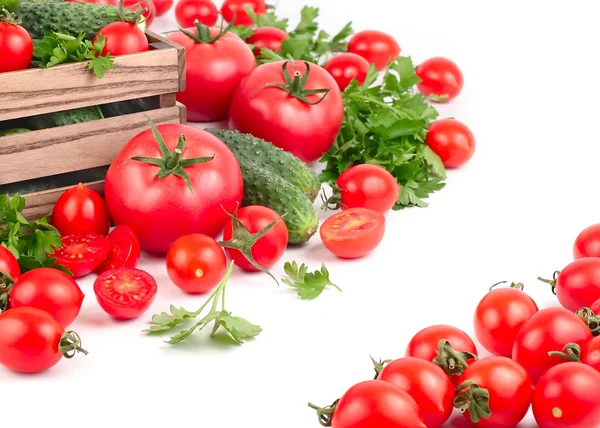 Tomates y pepinos frescos en una caja de madera sobre un fondo blanco con espacio para el texto . — Foto de Stock