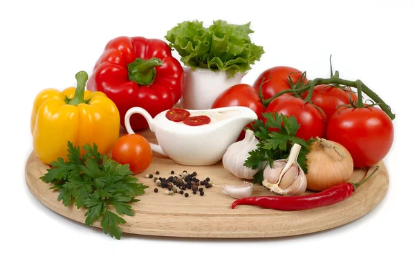 Fresh vegetables and sauce in a sauce-boat on a board on a white background. — Stock Photo, Image