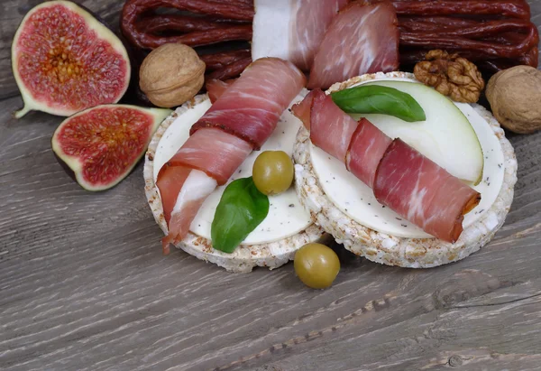 Schinken und Wurst auf einem Brett auf einem hölzernen Hintergrund. — Stockfoto