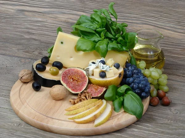 Fresh fruit and cheese on a wooden background. — Stock Photo, Image