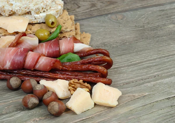 Jamón, salchichas ahumadas y queso sobre fondo de madera . — Foto de Stock
