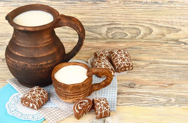 Melk in een kruik en cookies op een houten achtergrond. — Stockfoto