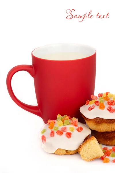 Taza roja con leche y galletas pequeñas con masilla de confitería sobre un fondo blanco . — Foto de Stock