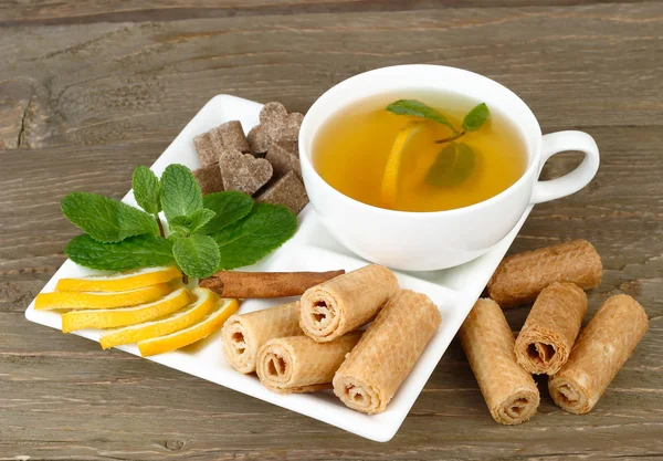 Tazza di tè verde con limone, cannella e menta su fondo di legno . — Foto Stock