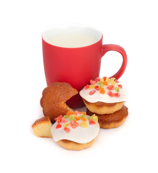 Taza roja con leche y galletas pequeñas con masilla de confitería sobre un fondo blanco . — Foto de Stock