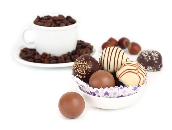 Chocolates and cup with coffee grains on a background on a white background. — Stock Photo, Image