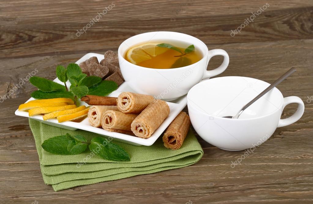 Cup of green tea with cinnamon, a lemon and mint on a rustic a wooden background.