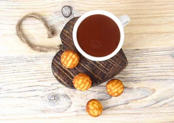 Copa de chocolate caliente fragante y galletas sobre un fondo de madera en el corazón de madera . — Foto de Stock