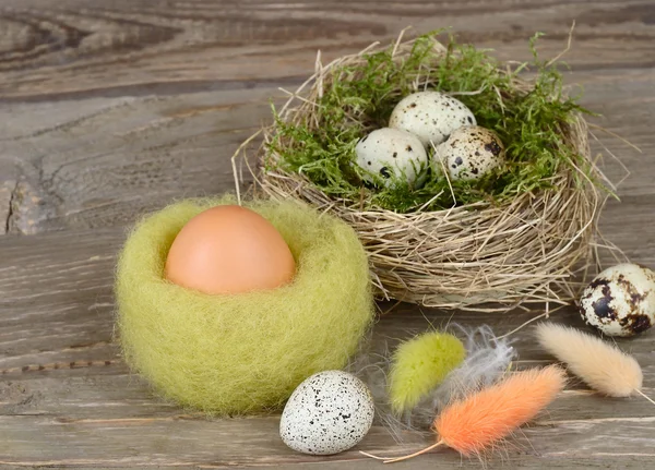 Huevos de Pascua en nidos y plumas sobre un fondo de madera. Fondo de Pascua . — Foto de Stock