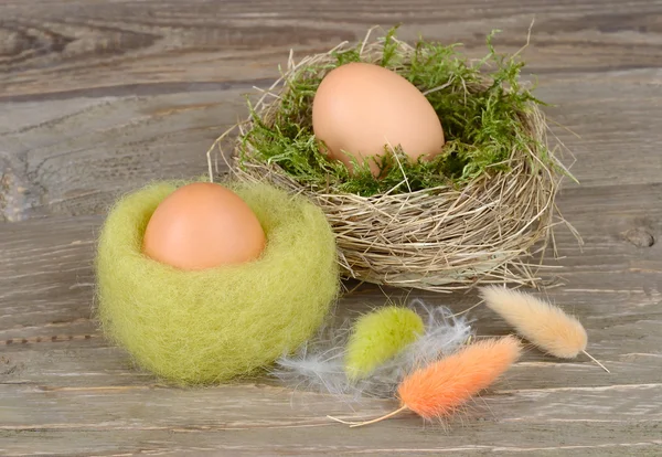 Ovos de Páscoa em ninhos e penas em um fundo de madeira. Fundo pascal . — Fotografia de Stock