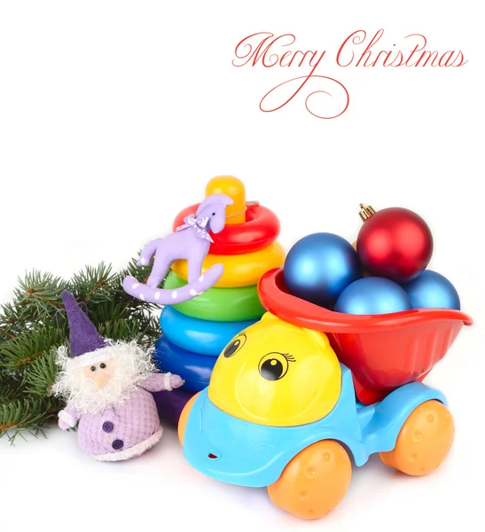 Julgranskulor med barns leksaksbil och en pyramid på en vit bakgrund. Jul bakgrund. — Stockfoto