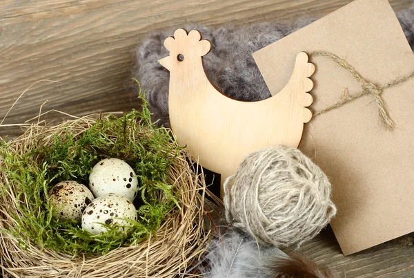 Easter eggs in a nest and wooden chicken on a wooden background. Easter background. — Stock Photo, Image