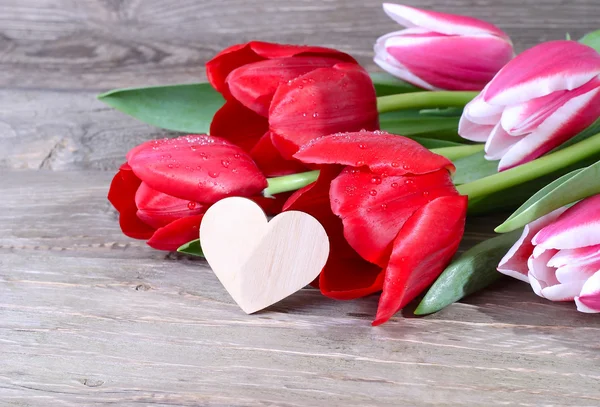 Tulipani freschi e cuore su uno sfondo di legno. Fiori per gli amanti . — Foto Stock