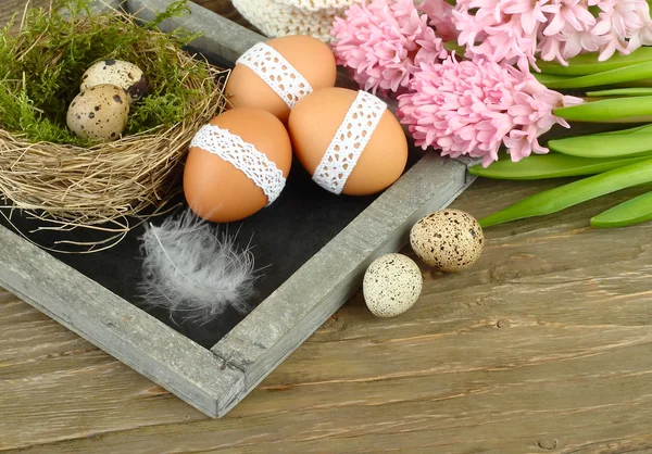 Pink hyacinths and Easter eggs on a blackboard (a cretaceous board) on wooden a rustic a background. Easter background. — Stock Photo, Image