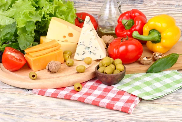 各种等级、 新鲜的蔬菜和橄榄轻木背景上的奶酪。制备的意大利素食比萨配料. 图库图片