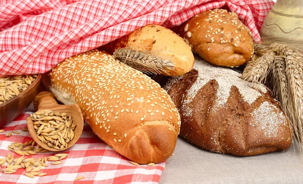 Pan fresco fragante bajo una servilleta a cuadros roja . — Foto de Stock