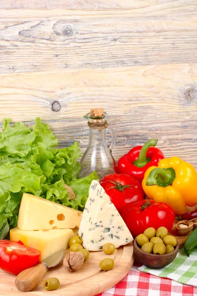 Käse verschiedener Sorten, frisches Gemüse und Oliven auf hellem Holzgrund. Zutaten für die Zubereitung der italienischen vegetarischen Pizza. — Stockfoto