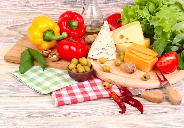 Fromage de différentes qualités, légumes frais et olives sur fond de bois clair. Ingrédients pour la préparation de la pizza végétarienne italienne . — Photo