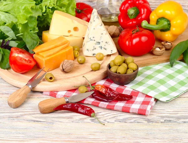 Cheese of various grades, fresh vegetables and olives on a light wooden background. Ingredients for preparation of the Italian vegetarian pizza. — Stock Photo, Image