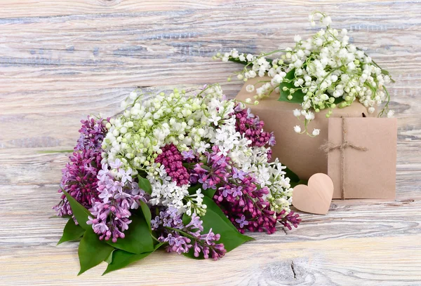 Fiori di primavera affascinanti di un lilla e gigli della valle e scatole di regalo su uno sfondo di legno. Uno sfondo per il tema "vacanza" con spazio per il testo . — Foto Stock