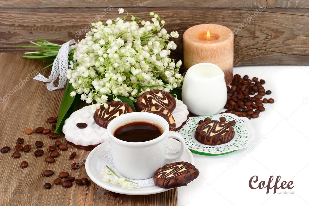 Cup of fragrant coffee with cookies and a bunch of lilies of the valley on a white background.