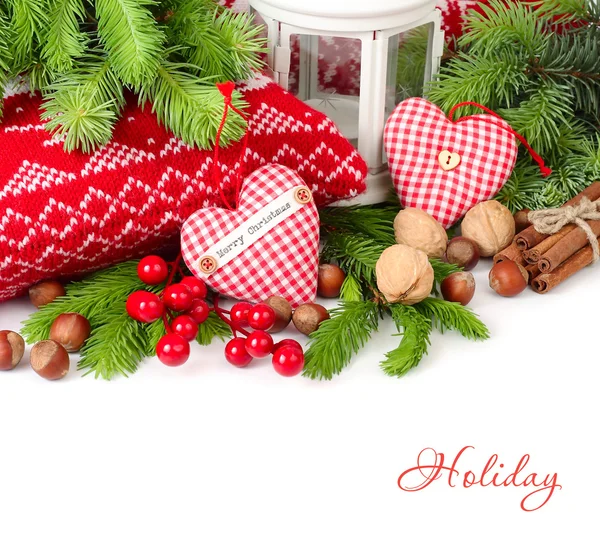 Textile Herzen, Nüsse und Zimt neben gestrickten Kissen und Zweigen eines Weihnachtsbaums auf weißem Hintergrund. Weihnachtlicher Hintergrund. — Stockfoto