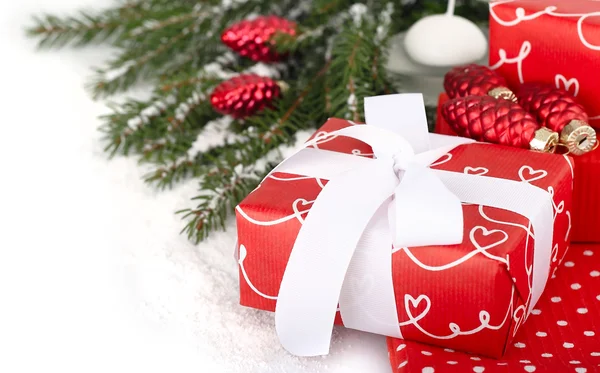 Red gift box and glass cones on branches of a Christmas tree on a white background. — Stockfoto
