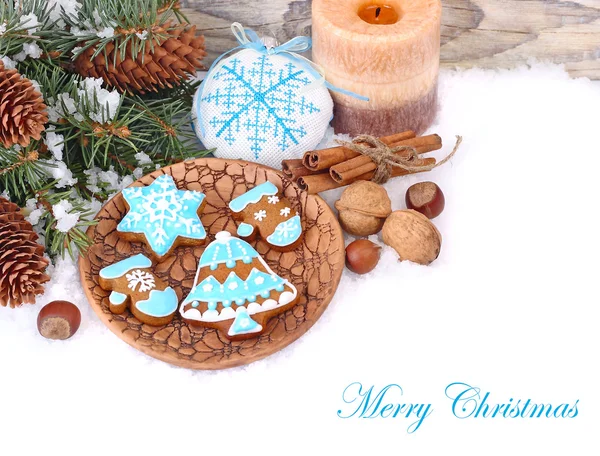 Ginger cookies and nuts near branches of a Christmas tree and cones on snow on a white background. A Christmas background with a place for the text. — Stock Photo, Image