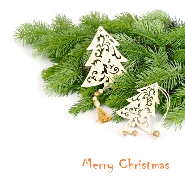 Wooden openwork fir-trees on fluffy branches of a Christmas tree on a white background. A Christmas background with a place for the text.