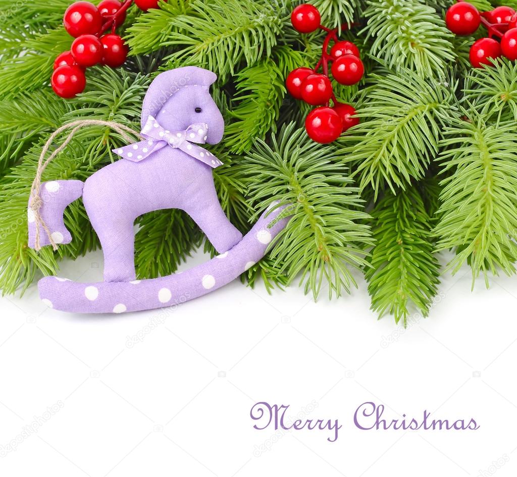 Violet textile horse, red berries and branches of a Christmas tree on a white background.