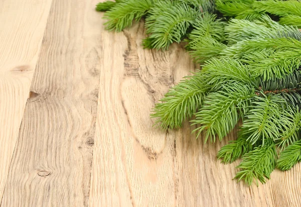 Las ramas esponjosas de un árbol de Navidad sobre un fondo de madera clara. Un fondo navideño con un lugar para el texto . —  Fotos de Stock