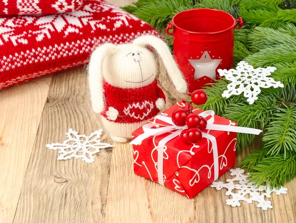 Knitted hare, candlestick, knitted snowflakes and red gift box on a wooden background. Christmas background. — Zdjęcie stockowe