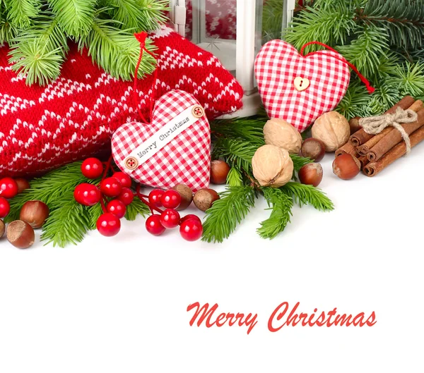 两个方格的纺织心、 红色浆果和分支的白色背景上的一棵圣诞树上的螺母。圣诞节背景以及放置文本的位置. 免版税图库图片