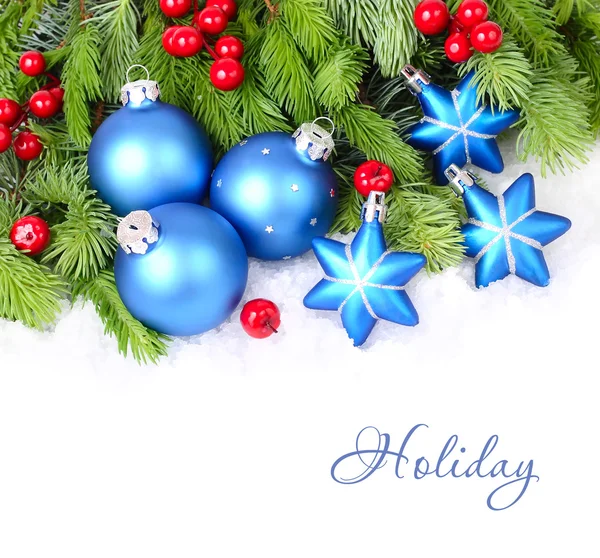 Mavi Noel topları ve yıldızlar ve kabarık beyaz zemin üzerinde bir Noel ağacı dalları üzerinde kırmızı meyveler. Bir Noel arka plan metni için bir yer ile.