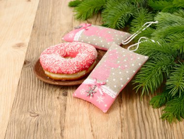 Kardan adam ve ahşap arka plan üzerinde bir Noel ağacının dalları üzerinde pembe bir poğaça ile pembe Tekstil yılbaşı ağacı süsleri.
