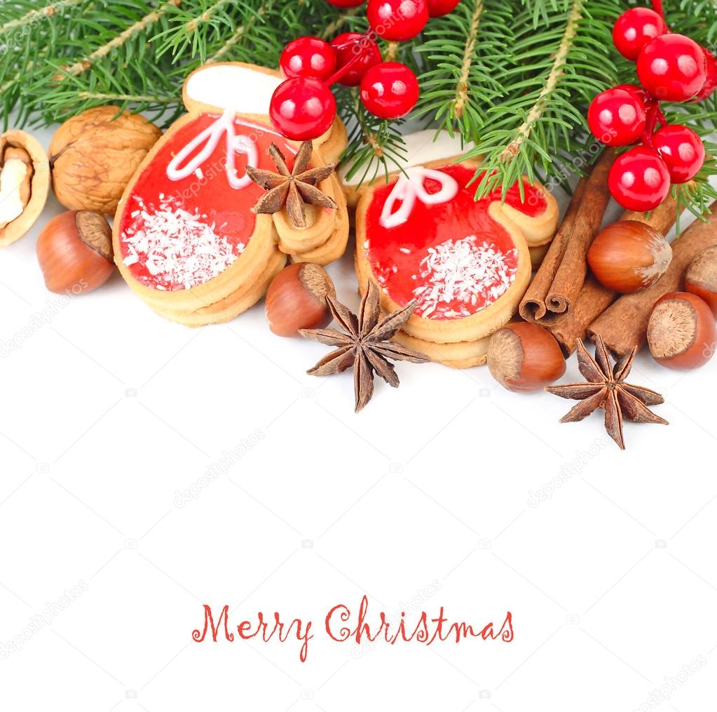 Ginger cookies in the form of mittens, nuts and red berries on branches of a Christmas tree on a white background. A Christmas background with a place for the text.