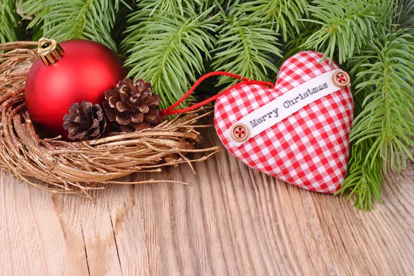 Červená kostkovaná textilní srdce a vánoční ozdoby na větvích vánočního stromku na dřevěné pozadí. Vánoční pozadí s místem pro text. — Stock fotografie