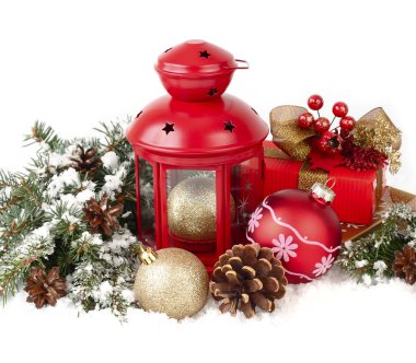 Red lamp candlestick, red and golden Christmas balls and cones on branches of a Christmas tree on a white background. A Christmas background with a place for the text.