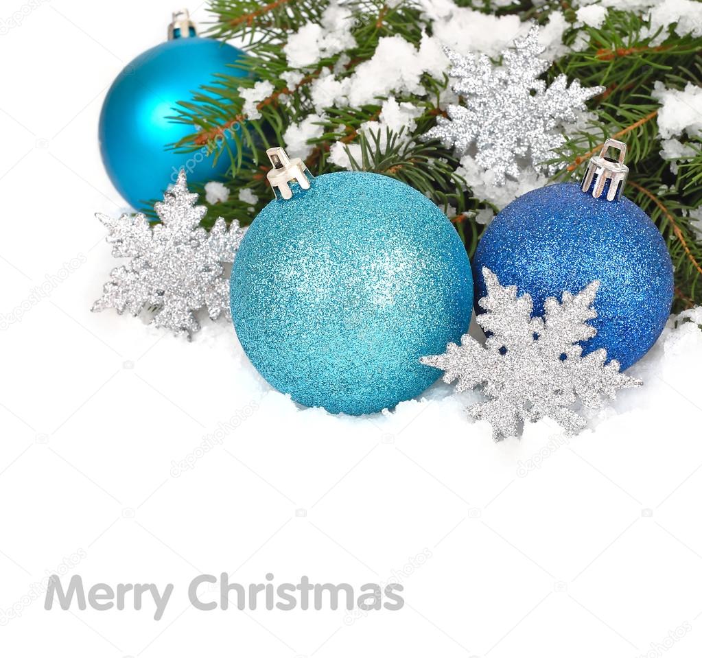 Blue Christmas balls and silvery snowflakes on snow-covered branches of a Christmas tree. A Christmas background with a place for the text.