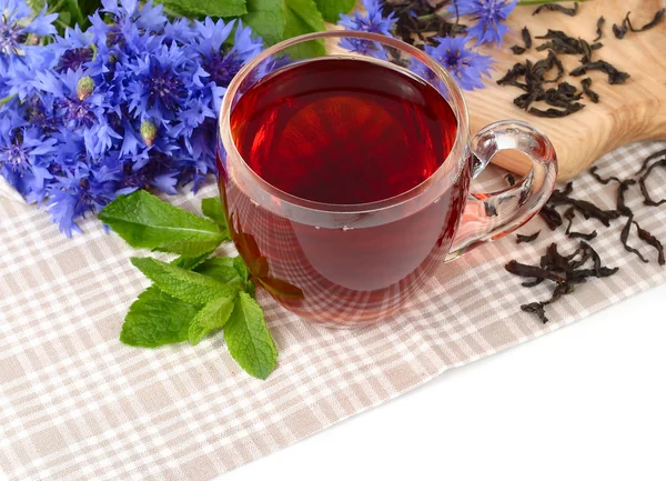 Xícara de chá preto com hortelã e flores de milho em um guardanapo de linho em um fundo branco . — Fotografia de Stock
