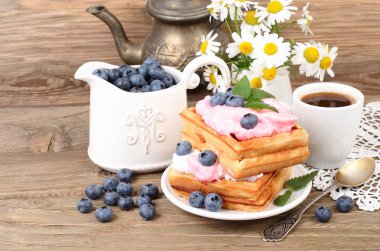 Fresh biscuits with bilberry mousse and blueberry on a wooden background.