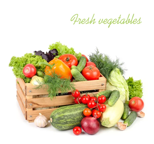 Verse rijpe groenten in een houten doos op een witte achtergrond met een plek voor de tekst. Stockfoto