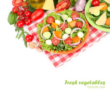 The Greek salad with cheese balls on an orange plate on a red checkered napkin and fresh ripe vegetables and herbs on a white background with a place for the text. clipart