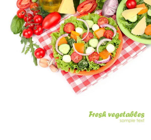 Grekisk sallad med ost bollar på en orange plattan på en röd rutig servett och färska mogna grönsaker och örter på en vit bakgrund med en plats för text. — Stockfoto