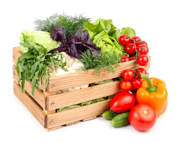 Verse rijpe groenten in een houten doos op een witte achtergrond met een plek voor de tekst. Stockafbeelding