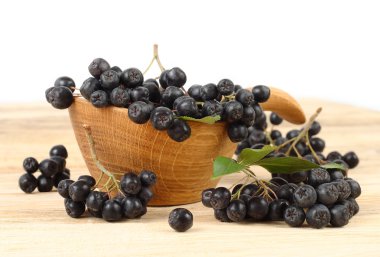 Siyah meyveli dağ kül beyaz zemin üzerinde bir ahşap kase.