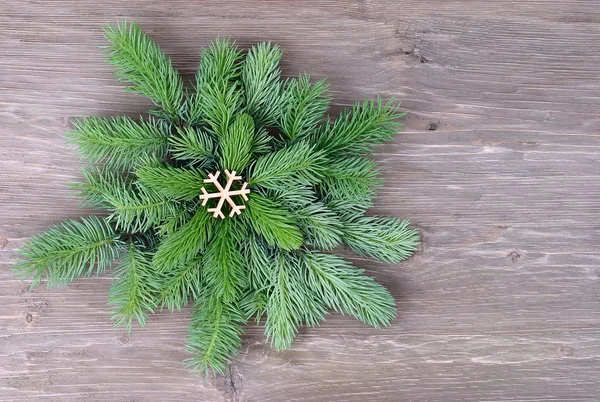 Schneeflocke aus flauschigen Tannenzweigen auf einem hölzernen Hintergrund. ein weihnachtlicher Hintergrund mit einem Platz für den Text. — Stockfoto