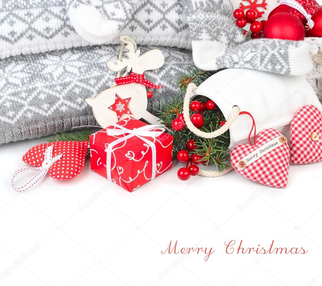 Christmas composition with red textile hearts, a red gift box and Christmas-tree decorations in the Scandinavian style on a white background. A Christmas background with a place for the text.